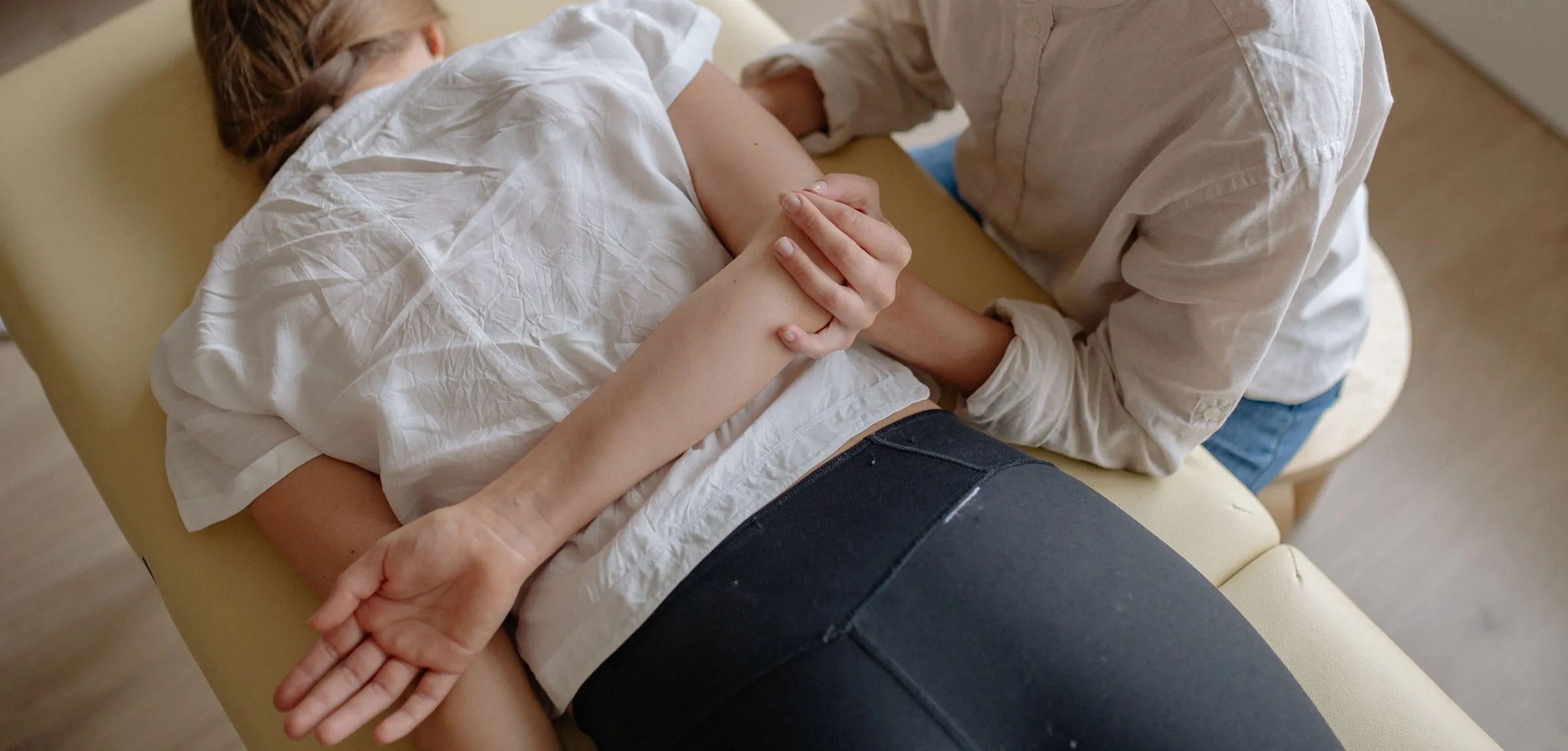 Seen from above, a chiropractor works on the shoulder blade of a patient lying face down on a treatment table