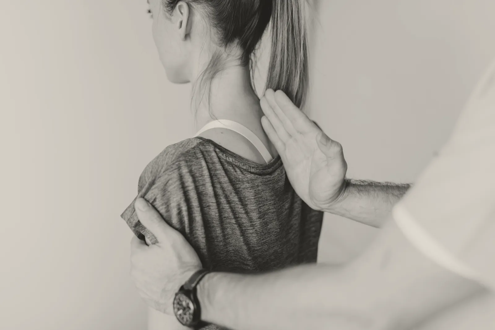 A chiropractor's hands assessing a patient's cervical spine